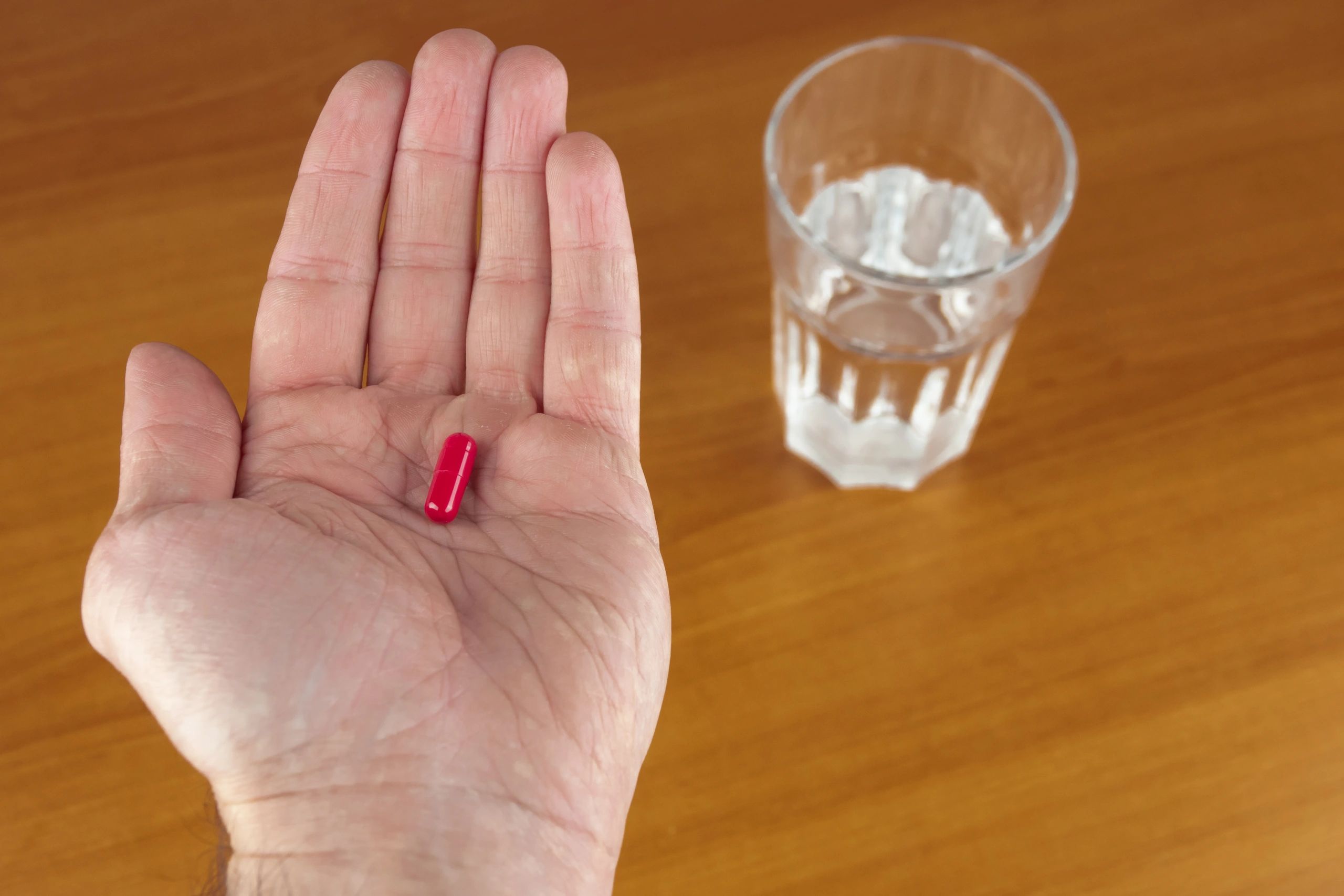 Person holding a pill and glass of water