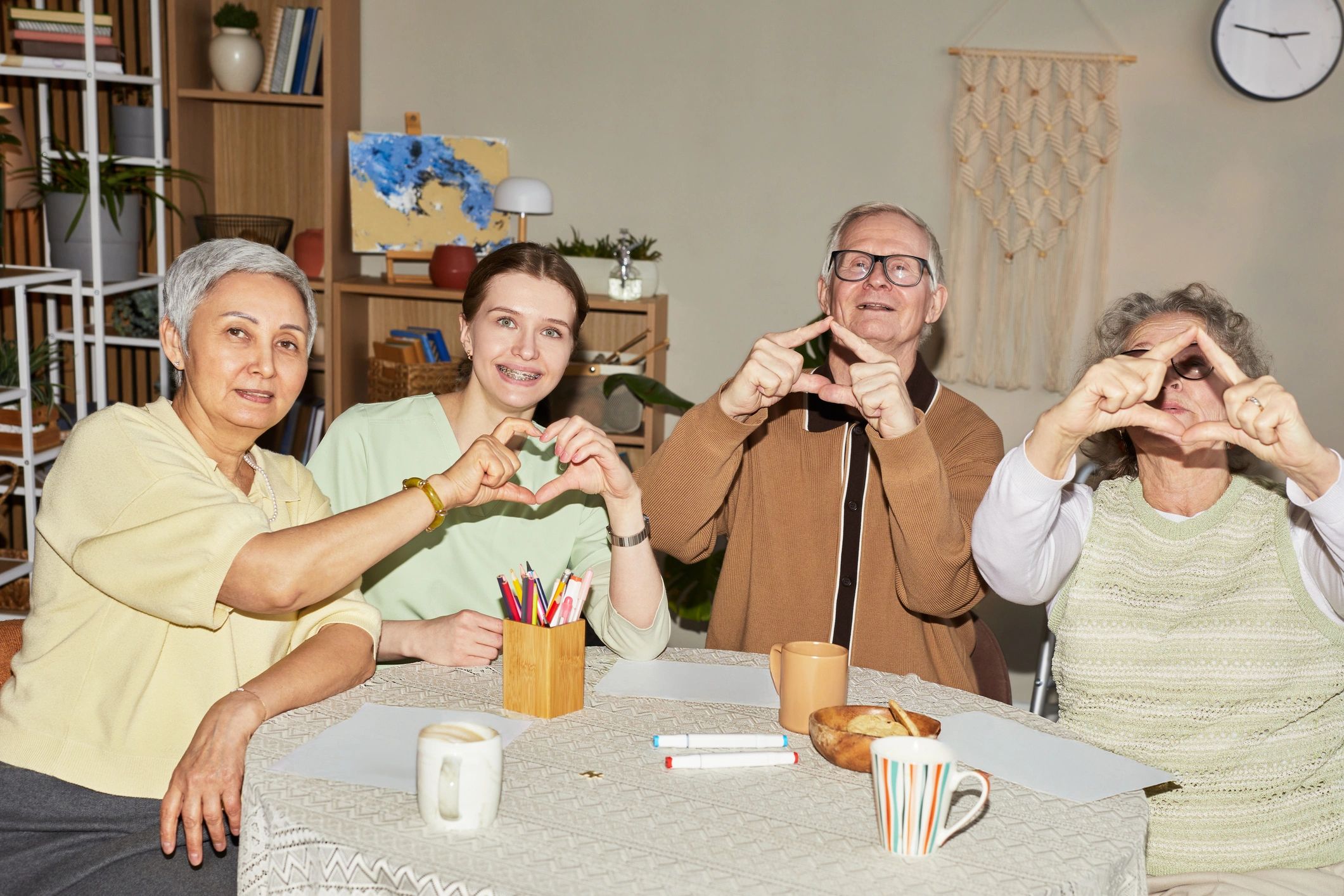 Senior residents and caregiver making heart signs